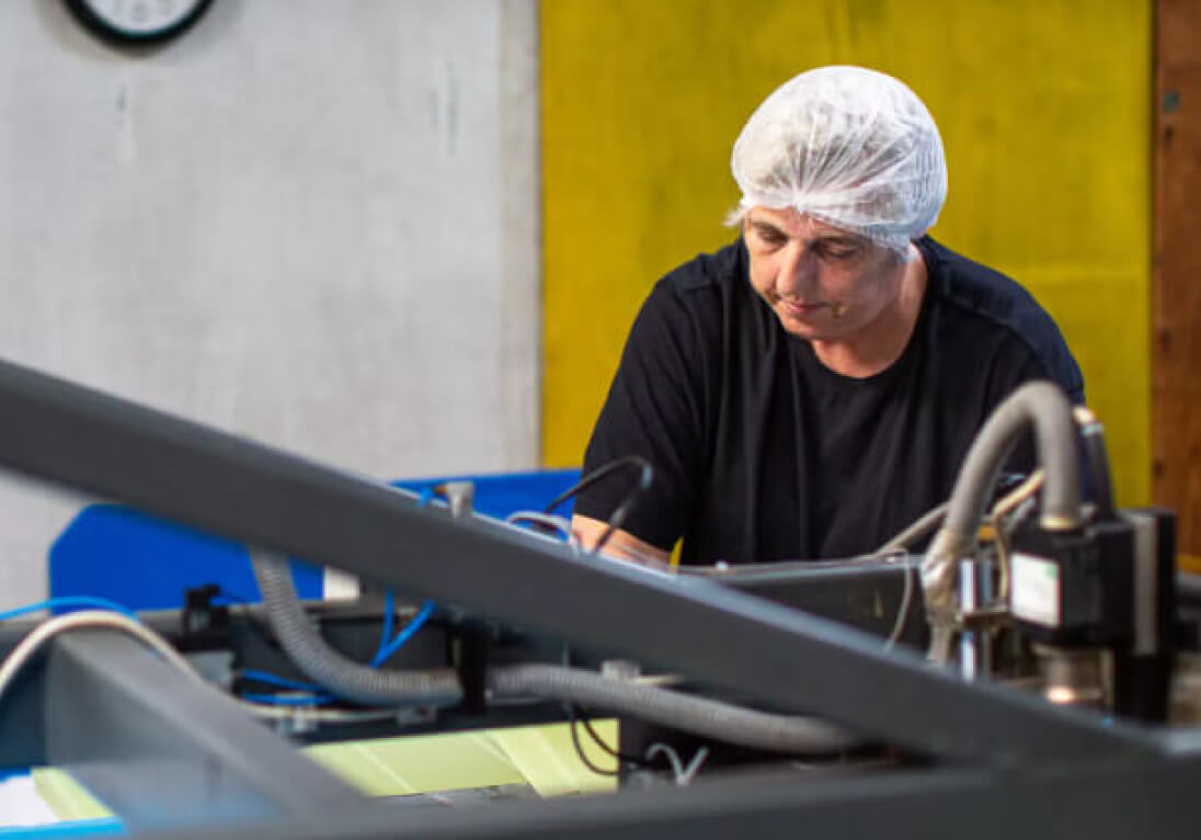 Man in a hairnet creating boxes for seafood packaging